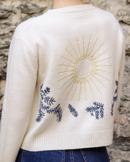 Close-up of the hand-embroidered sun and floral design on the back of the natural white Adele & Soleil Jour de Soleil sweater.