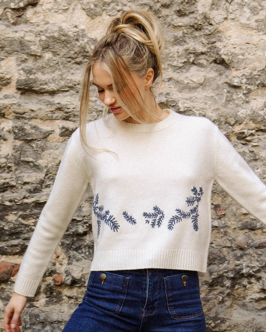 Close-up of the hand-embroidered floral detail on the natural white Adele & Soleil Jour de Soleil sweater, front view.