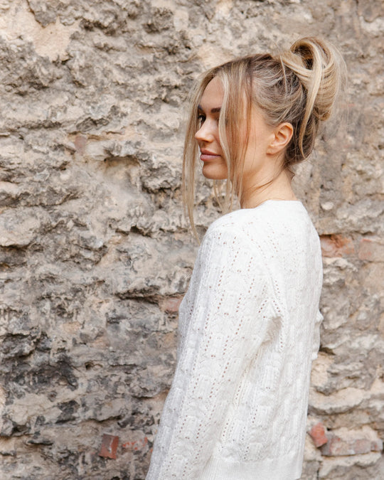 Side view of a woman wearing the fitted Adele & Soleil Brise chalk white textured cardigan.
