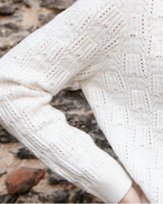 Close-up of the sleeve and geometric textured knit pattern of the Adele & Soleil Brise chalk white cardigan.