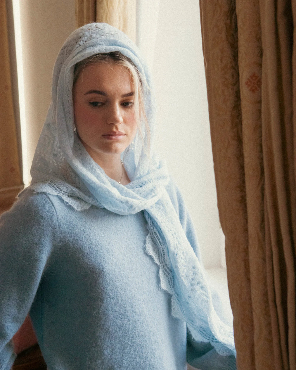 Woman wearing the Adele & Soleil Brouillard light blue triangle scarf styled over her head and shoulders.