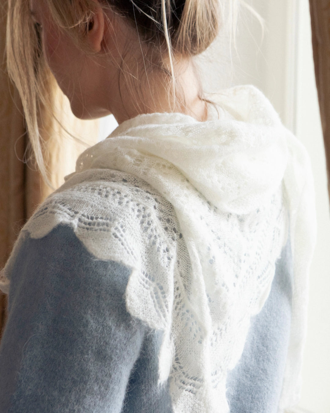 Back view of the Adele & Soleil Brouillard natural white triangle scarf softly draped over a woman’s shoulders.