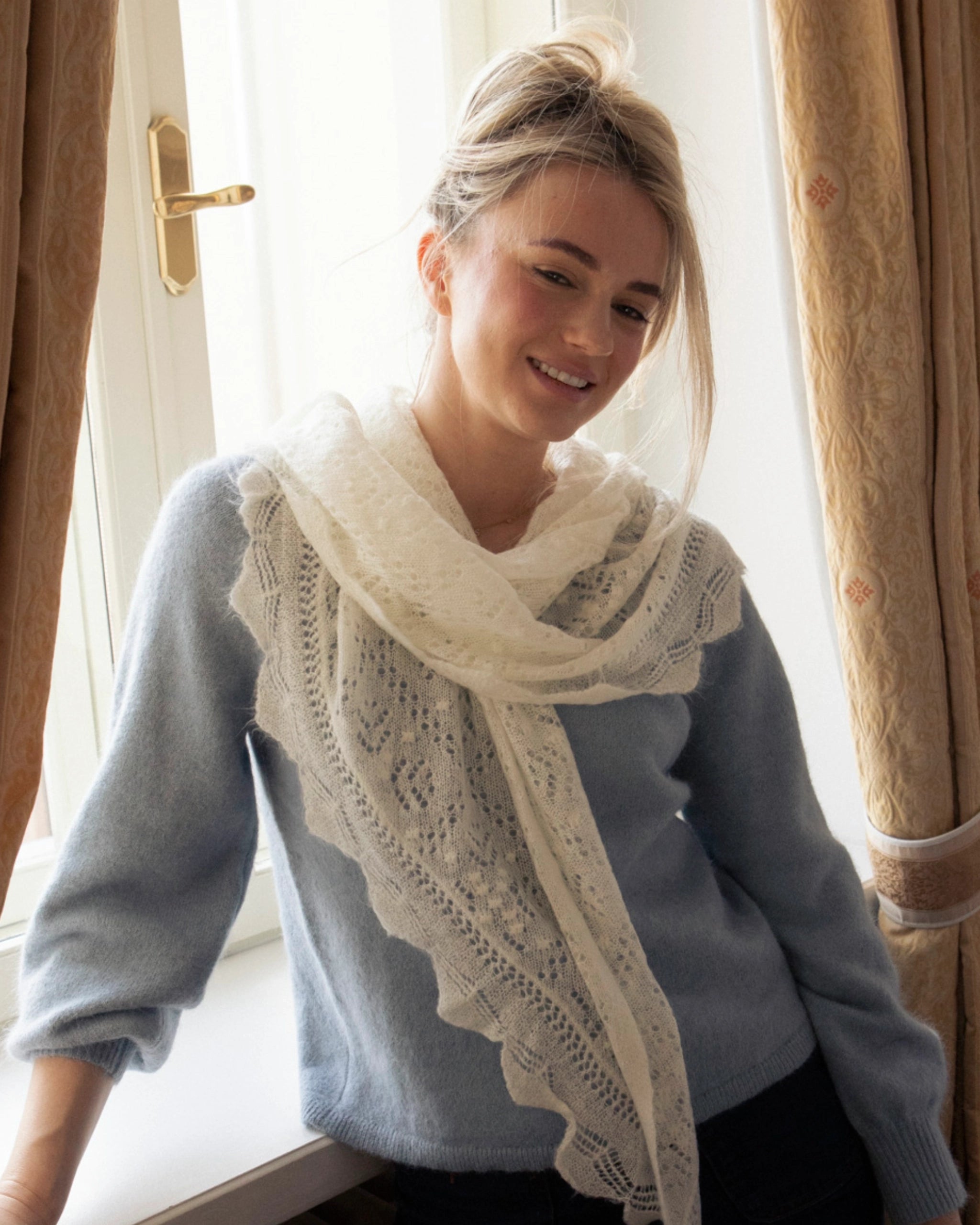 Front view of a woman wearing the Adele & Soleil Brouillard natural white lace-knit triangle scarf.