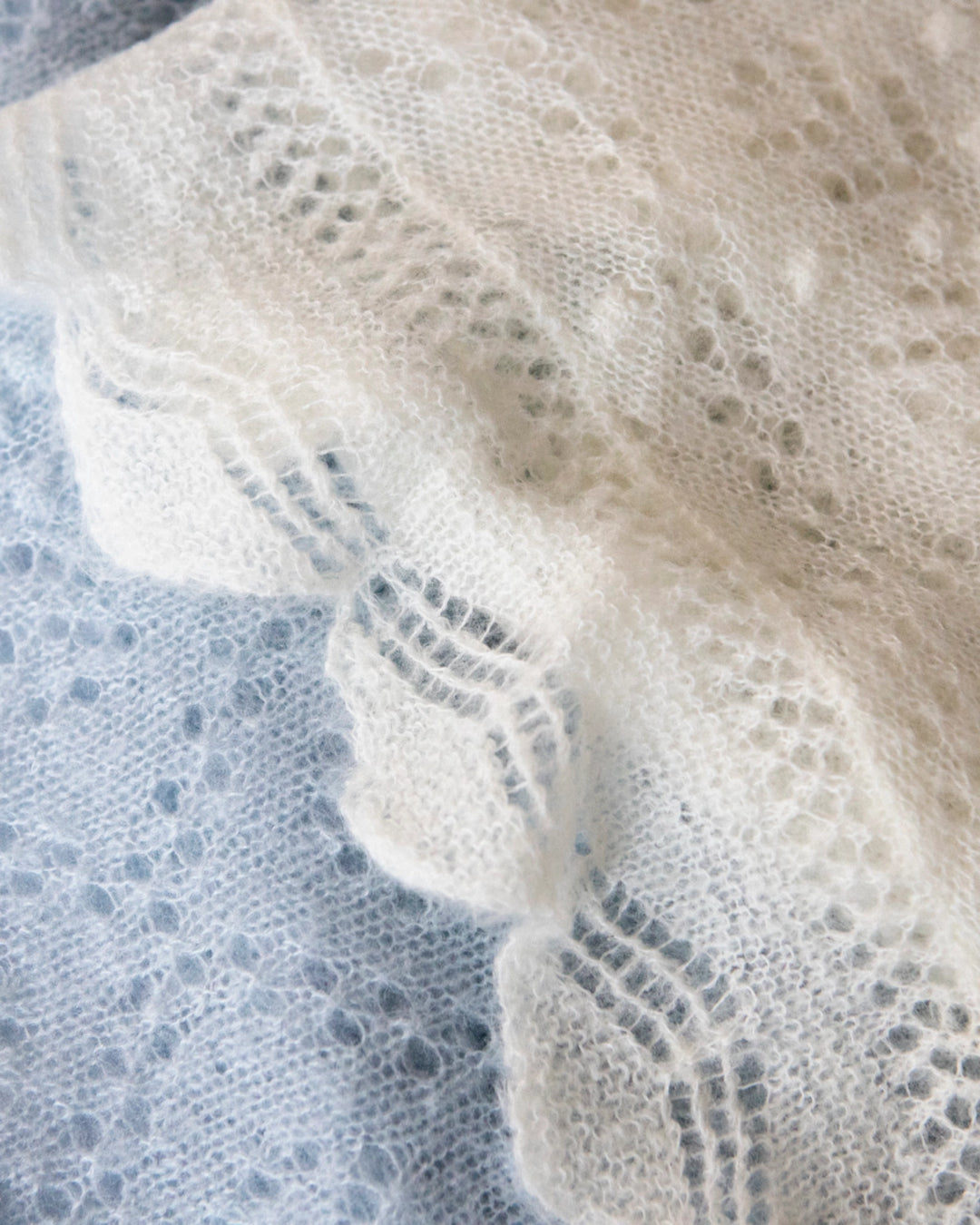 Close-up of the delicate lace-knit pattern of the Adele & Soleil Brouillard triangle scarf in white.