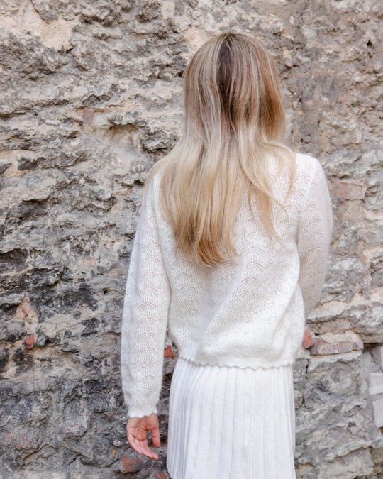 Woman wearing the natural white Adele & Soleil Fée V-neck knit sweater, back view.