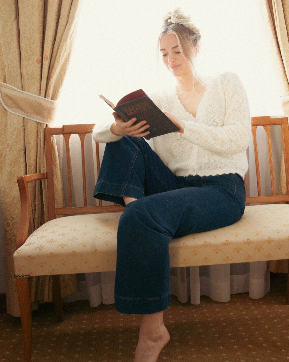 Woman wearing the natural white Adele & Soleil Fée V-neck knit sweater in a relaxed indoor setting.
