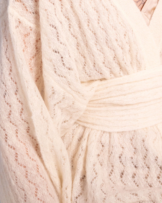 Close-up of the crossover front and delicate textured knit of the Adele & Soleil Jasmin natural white wrap cardigan.