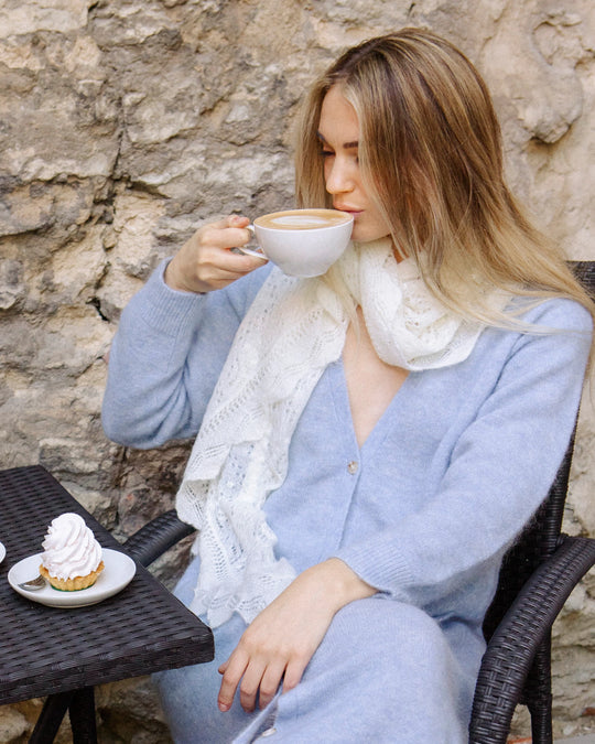 Woman wearing the Adele & Soleil Lundi Matin sky blue longline cardigan, seated at an outdoor café.