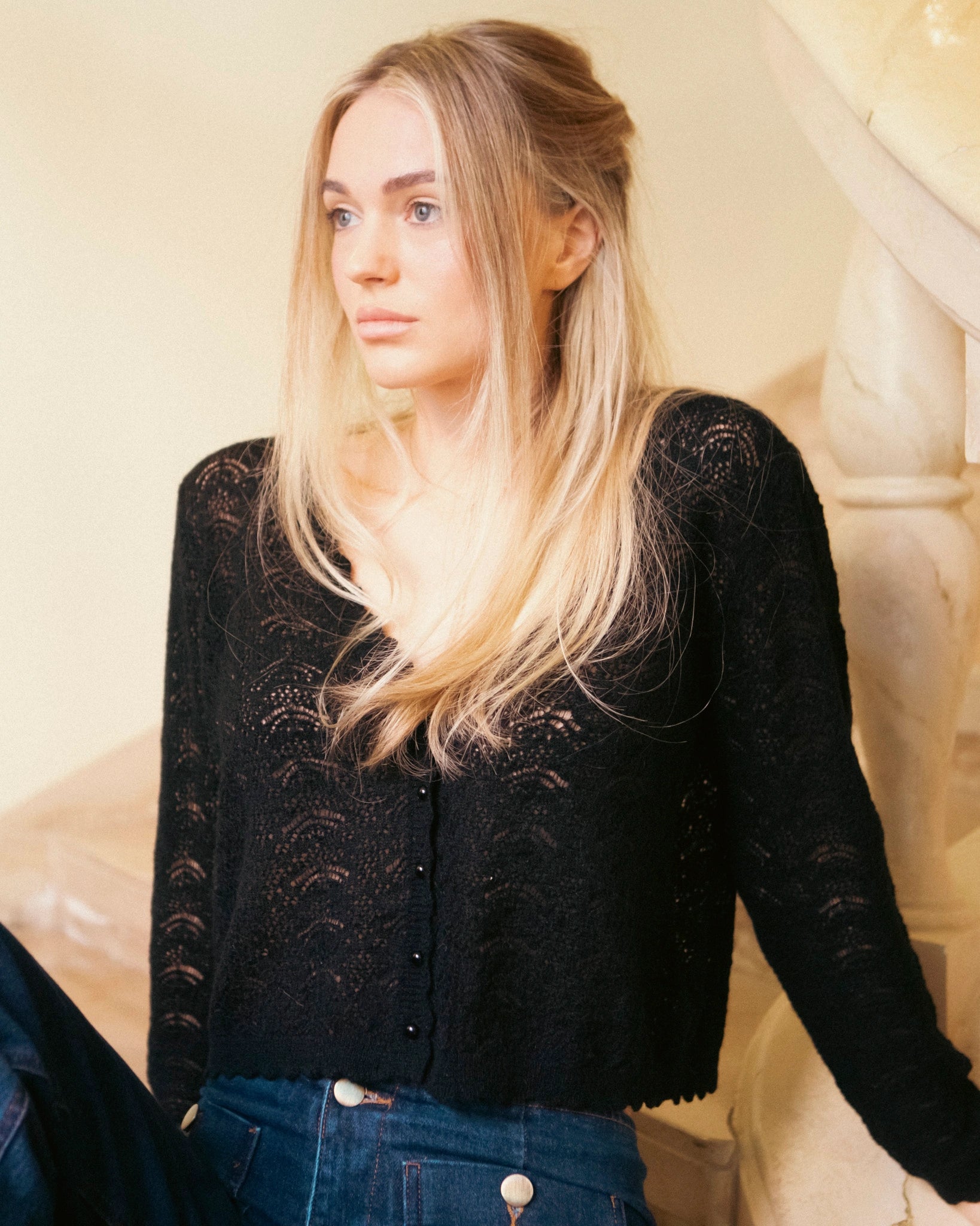Woman wearing the black Adele & Soleil Rêve V-neck sweater with blue jeans, half-body front view.