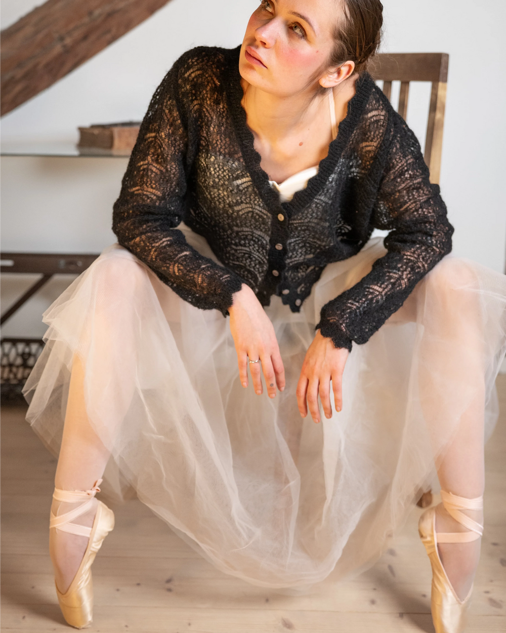 Seated woman wearing the black Adele & Soleil Rêve V-neck sweater with a flowing tulle skirt.