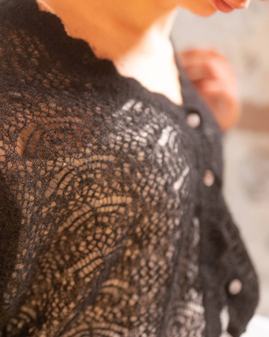 Close-up of the sheer knit texture on the black Adele & Soleil Rêve V-neck sweater.