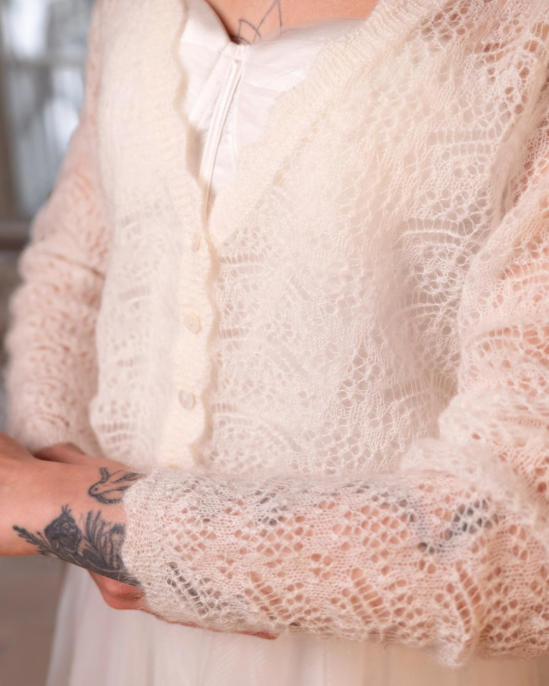 Close-up of the neckline and front knit detail of the natural white Adele & Soleil Rêve sweater.