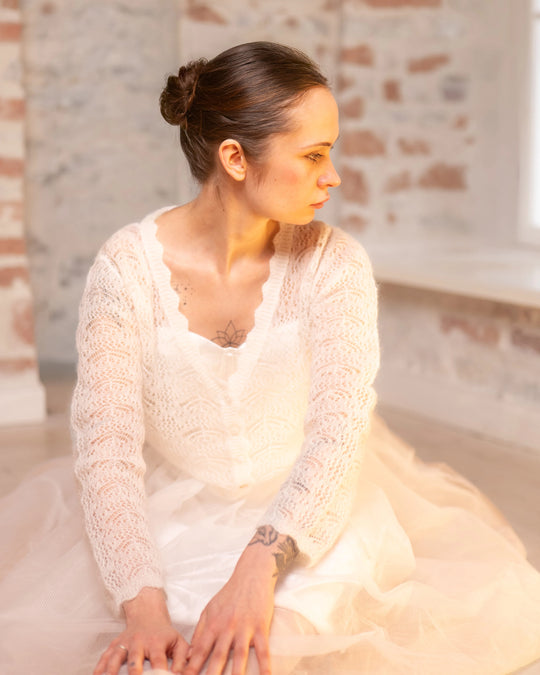 Seated woman wearing the natural white Adele & Soleil Rêve V-neck sweater, front view.