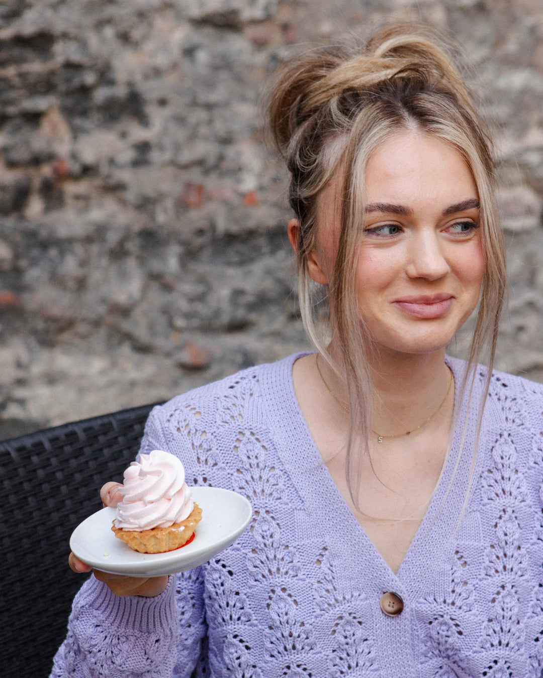 Woman seated with a cupcake while wearing the Adele & Soleil Sérène lavender textured cotton cardigan.