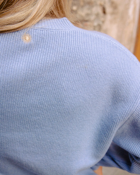 Close-up of the golden embroidered sun at the back neckline of the Adele & Soleil Toujours sky blue merino cardigan.