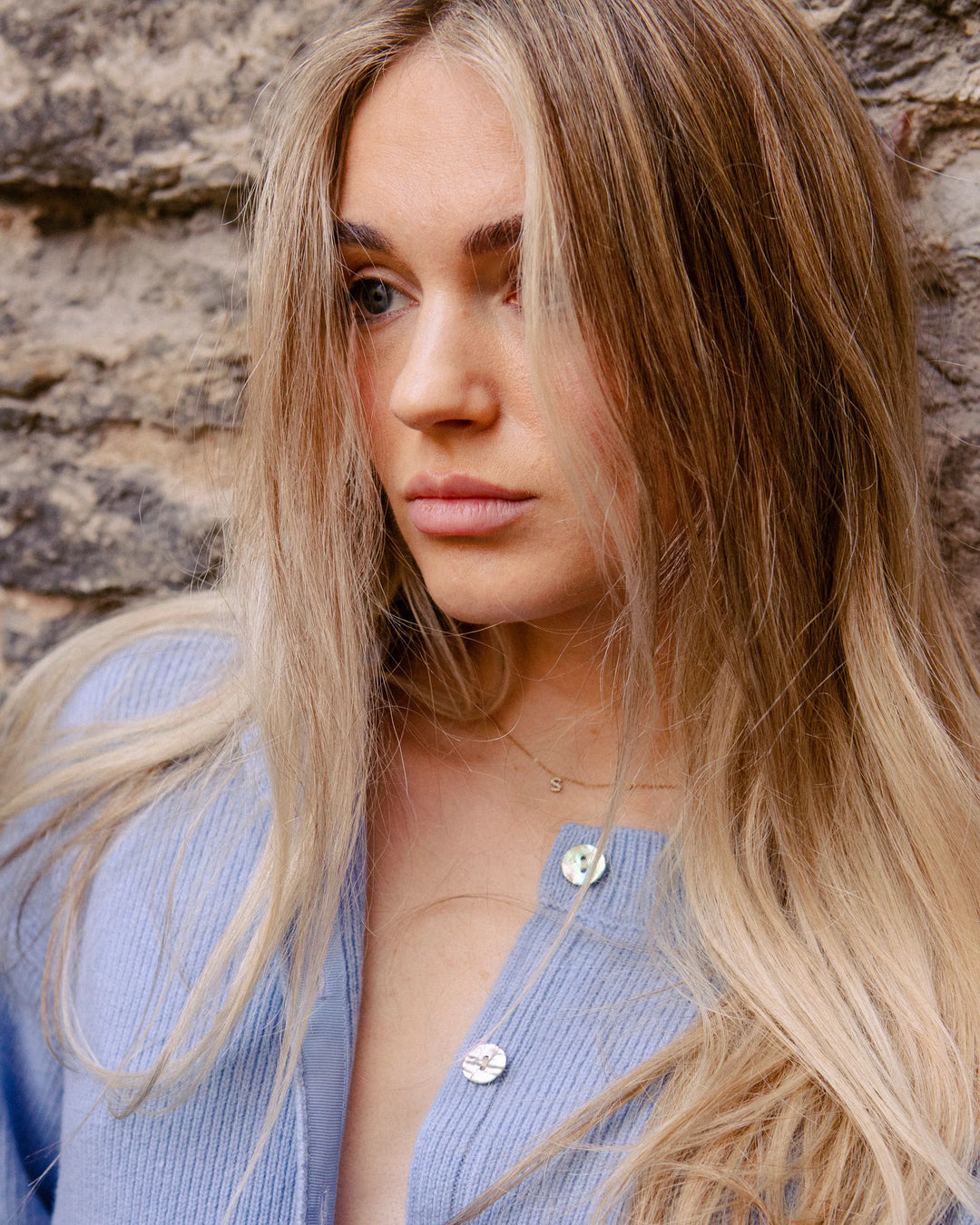 Close-up of a woman wearing the Adele & Soleil Toujours sky blue merino wool cardigan with shell buttons.