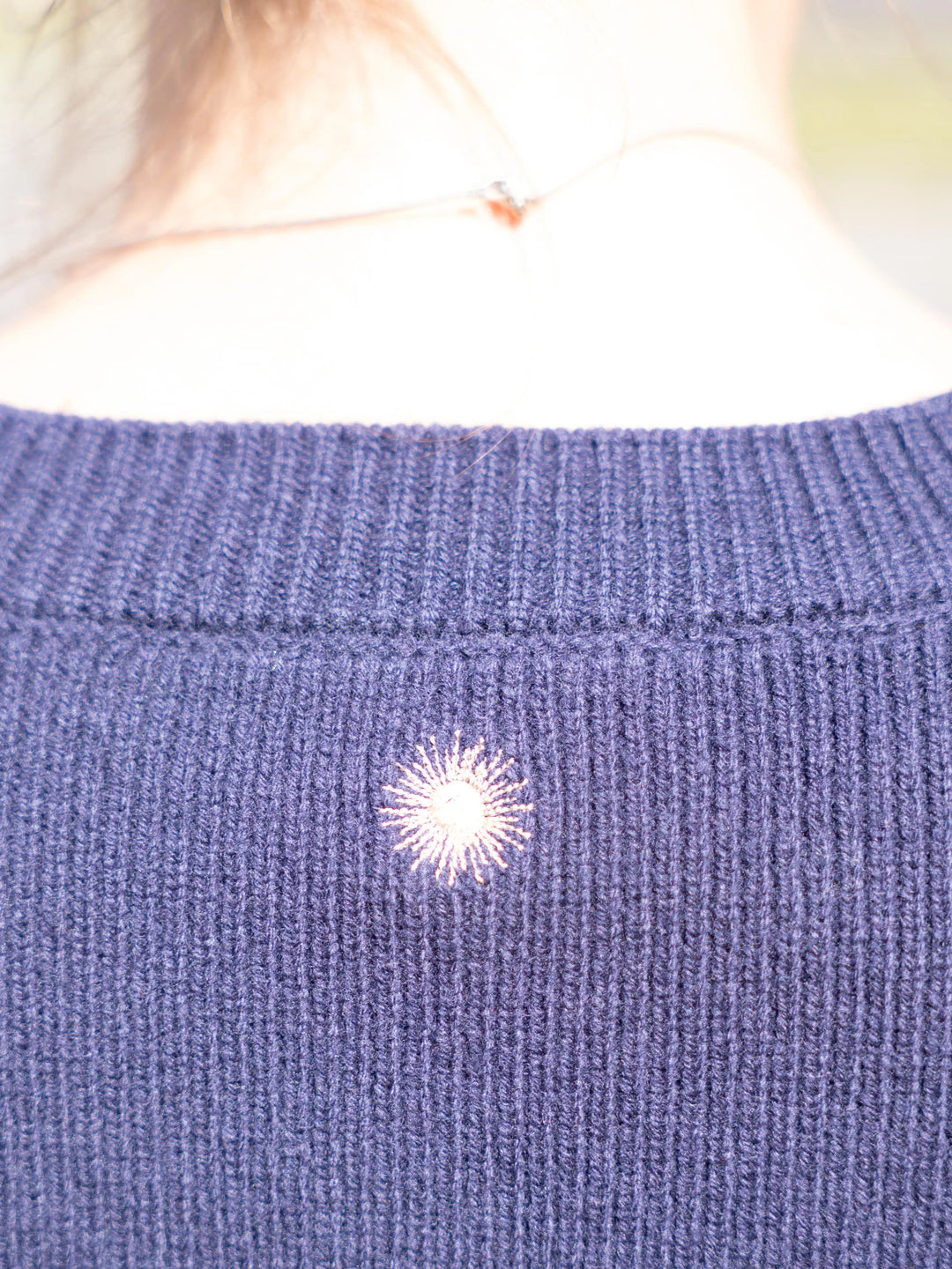 Close-up of  sun embroidery at the back of the Toujours 100% merino wool cardigan in Navy