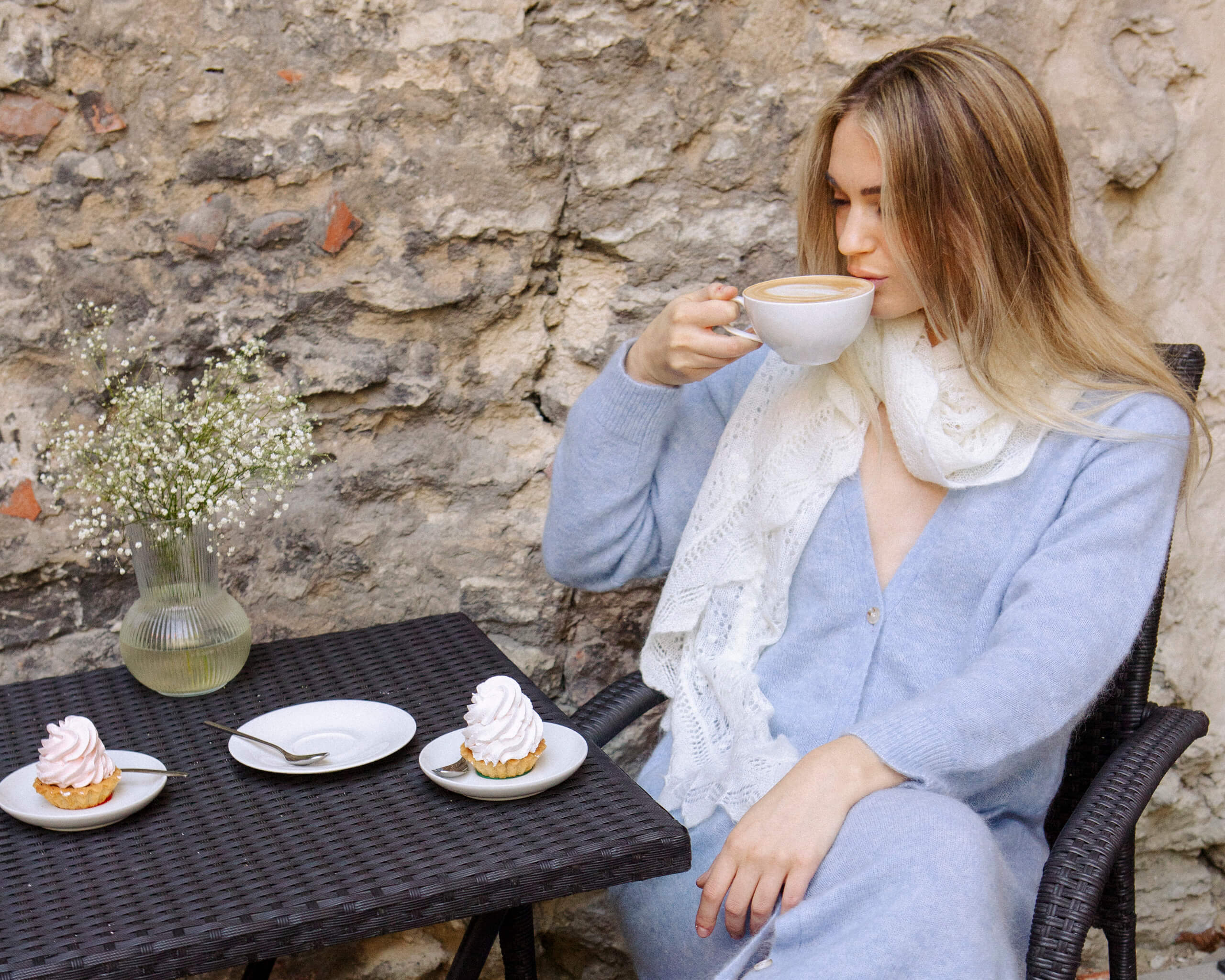 Woman wearing light blue Adele & Soleil Lundi Matin cardigan outdoors beside a table.